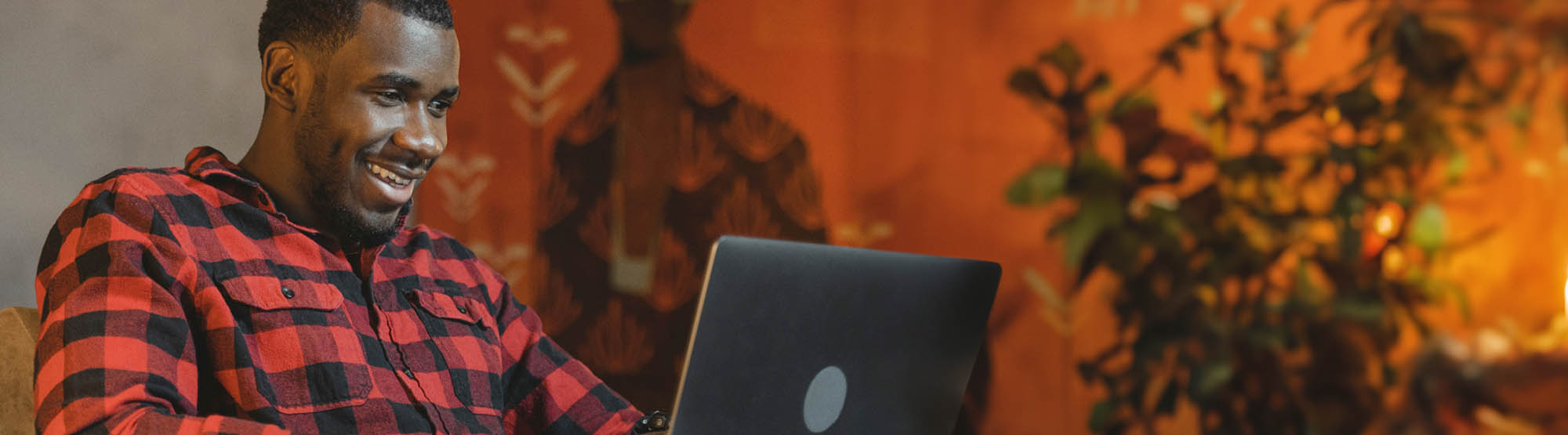 Man in red flannel shirt using a laptop computer