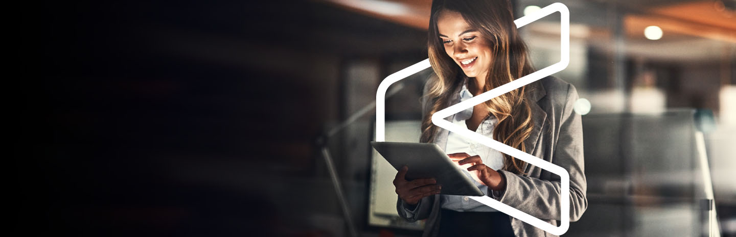 A woman using a tablet with light shining on her face. She is inside of a stylized bracket graphic.